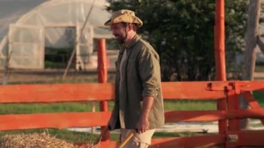 Şapkalı bir çiftçi saman arabasını bir yığın halinde çekiyor. Tarım işi