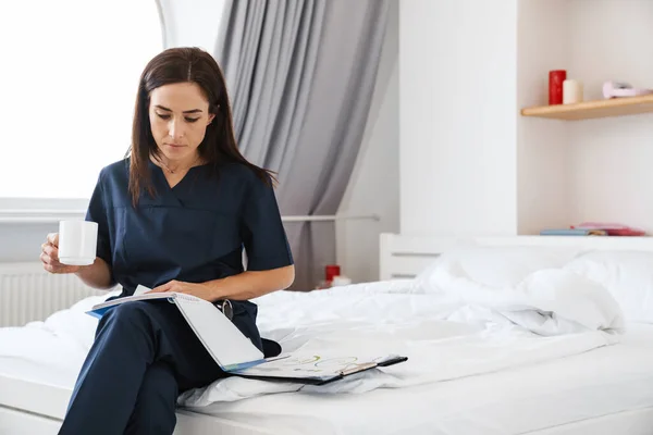 Brunette Woman Blue Medical Suit Sitting Bed Cup Her Hands — Stock Photo, Image