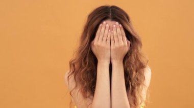 Neşeli bir kadın, sarı arka planda tek başına duran yüz duygularını gösterir.