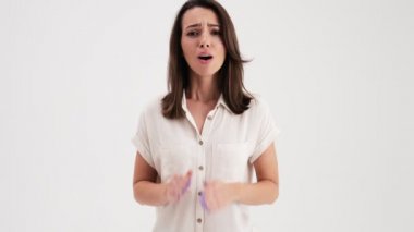 A beautiful woman wearing shirt is showing heartwarming gesture standing in the studio isolated over white background