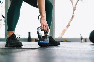 Beyaz sporcu kadın spor salonunda dambılla antrenman yapıyor.