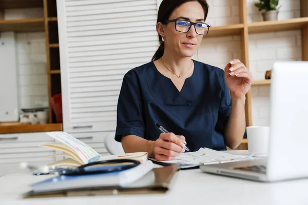 Een Vrouw Een Blauw Medisch Pak Een Bril Zittend Aan — Stockfoto