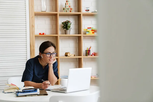 Een Vrouw Medisch Uniform Bril Koptelefoon Zittend Aan Een Tafel — Stockfoto