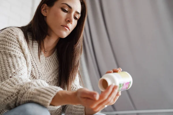 Una Donna Che Versa Pillole Barattolo Una Palma Mentre Siede — Foto Stock