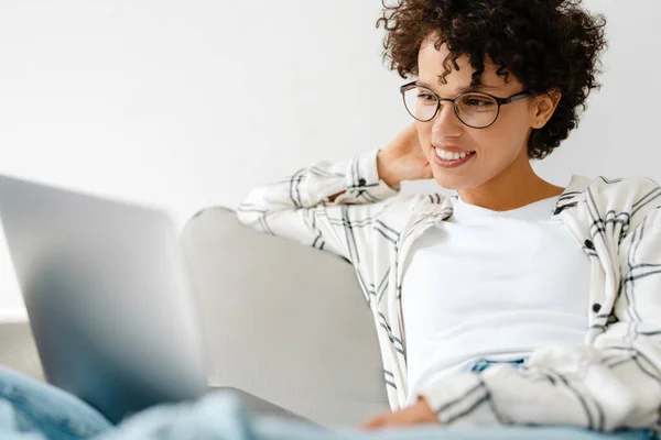 Young Curly Woman Smiling Using Laptop While Sitting Couch Home — Stock Photo, Image