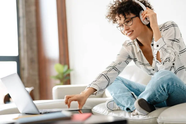 Junge Lockige Frau Mit Kopfhörer Mit Laptop Während Sie Hause — Stockfoto