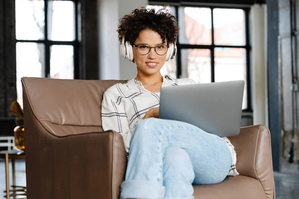 Ung Lockig Kvinna Hörlurar Använder Laptop När Sitter Fåtölj Hemma — Stockfoto