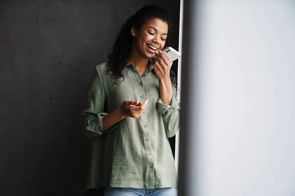 Negro Joven Mujer Usando Teléfono Móvil Mientras Apoya Pared Interior — Foto de Stock