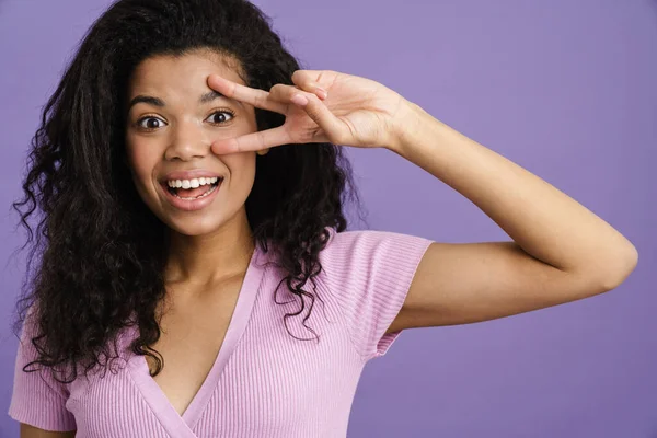 紫の背景に平和の印を当てながら笑う若い黒人女性 — ストック写真