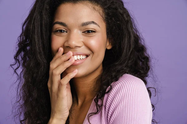 年轻的黑人女人笑着捂住嘴被紫色背景隔开 — 图库照片