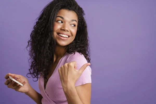 Nuori Musta Nainen Osoittaa Sormella Sivuun Käyttää Matkapuhelinta Eristetty Violetti — kuvapankkivalokuva