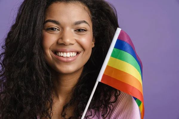紫の背景に隔離された虹の旗を振りながら笑顔若い黒人女性 — ストック写真