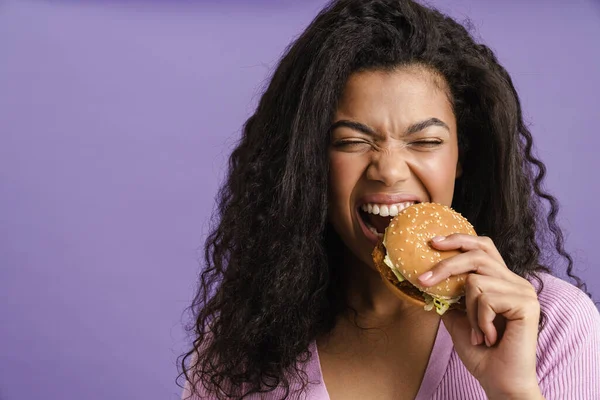 Jovem Mulher Negra Com Cabelo Encaracolado Rindo Enquanto Come Hambúrguer — Fotografia de Stock