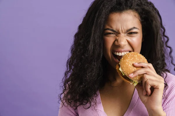 Young Black Woman Curly Hair Grimacing While Eating Hamburger Isolated — Stock Photo, Image