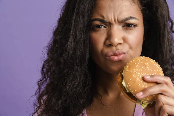 Young Black Woman Curly Hair Grimacing While Eating Hamburger Isolated — Stock Photo, Image