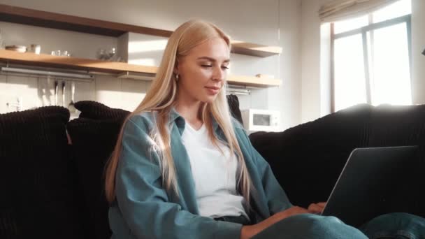 Una Hermosa Mujer Rubia Está Usando Portátil Sentado Sofá Dentro — Vídeo de stock