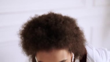 Müziği dinleyen rahat bir Afrikalı Amerikalı kadın kablosuz kulaklıklarını içeride koltukta oturuyor.