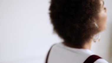 Müziği dinleyen mutlu bir Afro-Amerikalı kadın kablosuz kulaklıklarını içeride koltukta otururken kullanıyor.