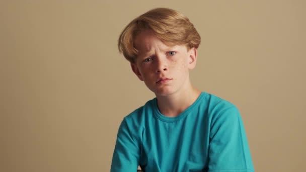 Zszokowany Chłopczyk Spogląda Kamerę Beżowym Tle Studiu — Wideo stockowe