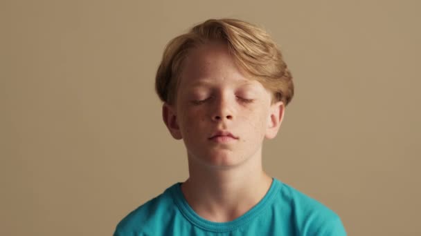 Улыбающийся Мальчик Открывает Глаза Смотрит Камеру Стоящую Изолированно Бежевом Фоне — стоковое видео