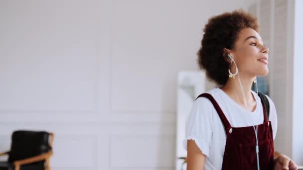 Positive African American Woman Walking While Enjoying Music Indoors — Stock Video