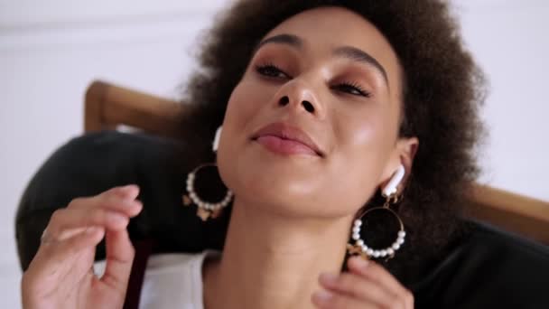 음악을 즐기는 아프리카 미국인 미소짓는 모습을 가까이 그녀의 이어폰을 사용하여 — 비디오