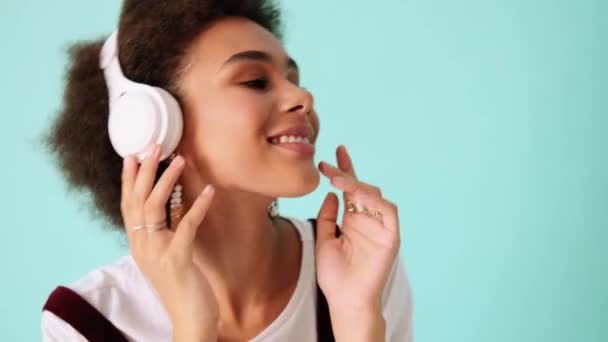 Smiling African American Woman Listening Music While Dancing Isolated Blue — Stock Video