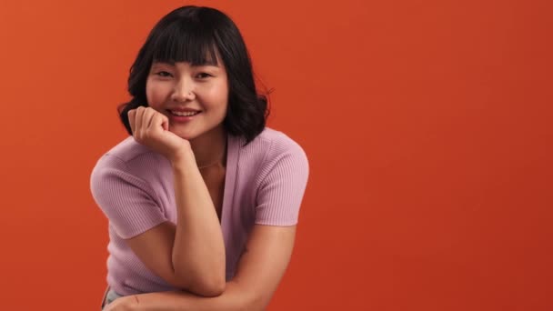 Une Femme Asiatique Heureuse Pose Caméra Isolée Sur Mur Orange — Video
