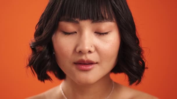在摄影棚的橙色墙壁上 一个正面的亚洲半裸女人的特写镜头出现在摄像机前 — 图库视频影像