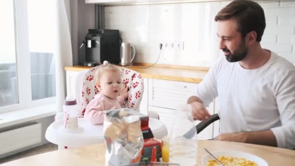 Een Gelukkige Vader Voedt Zijn Dochtertje Terwijl Een Kinderstoel Keuken — Stockvideo