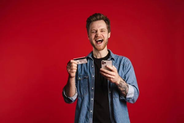Kırmızı Duvarın Arkasında Dikilen Mutlu Gülümseyen Genç Adam Cep Telefonu — Stok fotoğraf