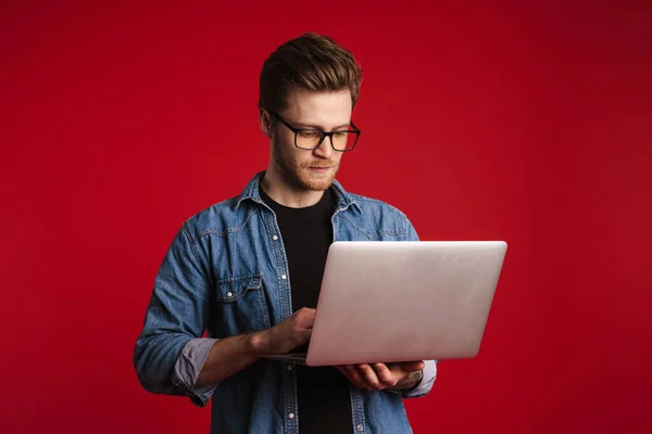 Jovem Calmo Roupas Casuais Sobre Fundo Parede Vermelha Segurando Computador — Fotografia de Stock