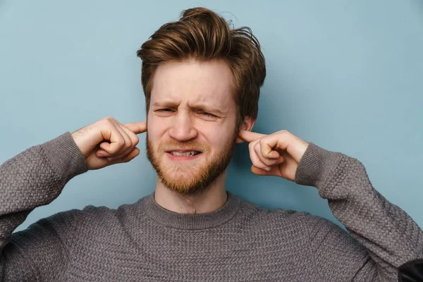 Skäggig Ingefära Man Rynkar Pannan Medan Pluggar Öronen Isolerade Över — Stockfoto