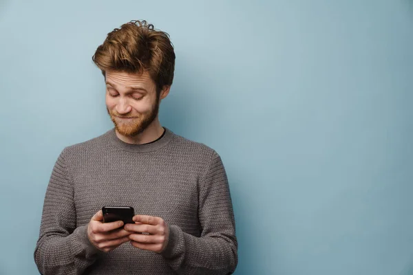 Білий Імбирний Чоловік Бородою Посміхається Використовує Мобільний Телефон Ізольовано Синьому — стокове фото