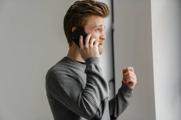 Ginger Young Man Talking Mobile Phone While Standing Indoors — Stock Photo, Image