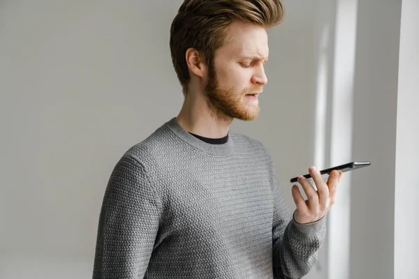 Ginger Young Man Talking Mobile Phone While Standing Indoors — Stock Photo, Image