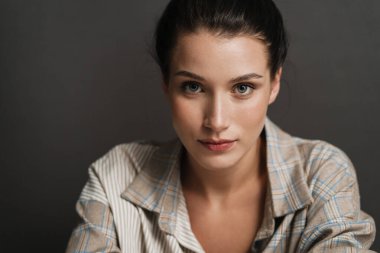 Genç, esmer, beyaz, sıradan bir kadının kameraya bakarken fotoğrafını çek.