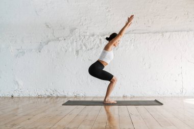 Stüdyo tarafındaki spor minderinin üzerinde esneyen zayıf esmer kadın.