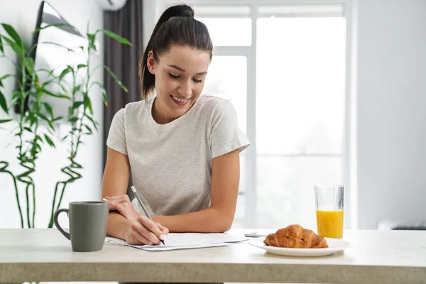 Mujer Sonriente Europea Escribiendo Notas Mientras Desayuna Cocina Casa — Foto de Stock