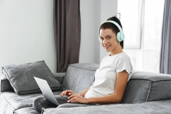 Europeo Donna Sorridente Utilizzando Cuffie Laptop Mentre Seduto Sul Divano — Foto Stock