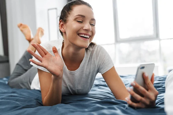 Evropská Usměvavá Žena Gestikuluje Používá Mobilní Telefon Zatímco Leží Doma — Stock fotografie