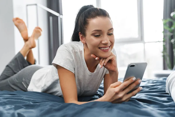 Mujer Sonriente Europea Usando Teléfono Móvil Mientras Está Acostada Cama —  Fotos de Stock