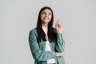 Genç esmer kadın gülümsüyor ve beyaz arka planda kendini dışlanmış olarak işaret ediyor.