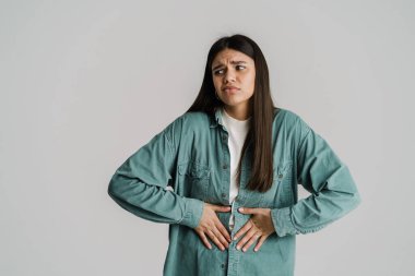 Karnı ağrıyan, göbeğini ovuşturan mutsuz genç bir kadın beyaz arka planda izole edilmiş.