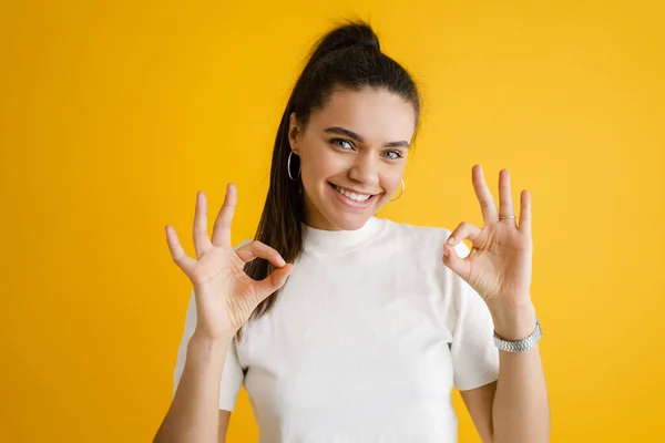 Joven Morena Sonriendo Mostrando Signo Aislado Sobre Fondo Amarillo —  Fotos de Stock
