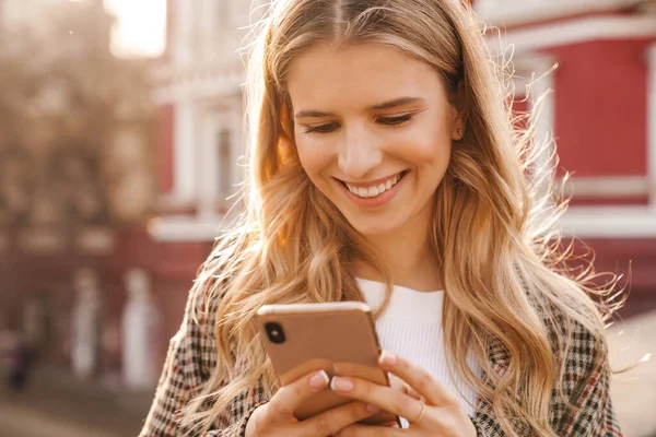 Glimlachende Jonge Blonde Vrouw Met Behulp Van Mobiele Telefoon Lopen — Stockfoto