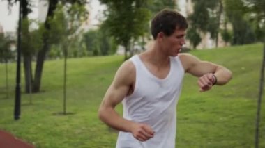 Kaslı bir adam spor salonunda spor takip cihazını kullanarak koşuyor.