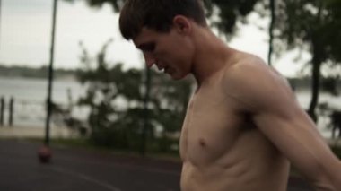 Spor sahasında antrenman yaparken kaslı bir adam iple atlıyor.