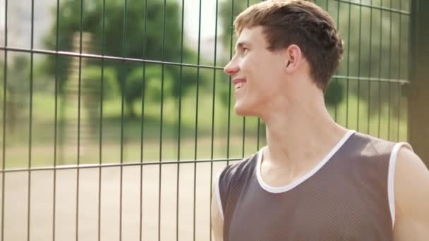 Chico Sonriente Está Mirando Gente Jugar Baloncesto Pie Patio Aire — Vídeos de Stock