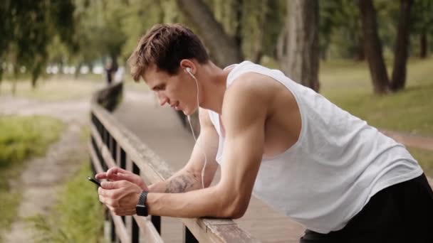 Cara Feliz Com Fones Ouvido Está Usando Seu Celular Enquanto — Vídeo de Stock